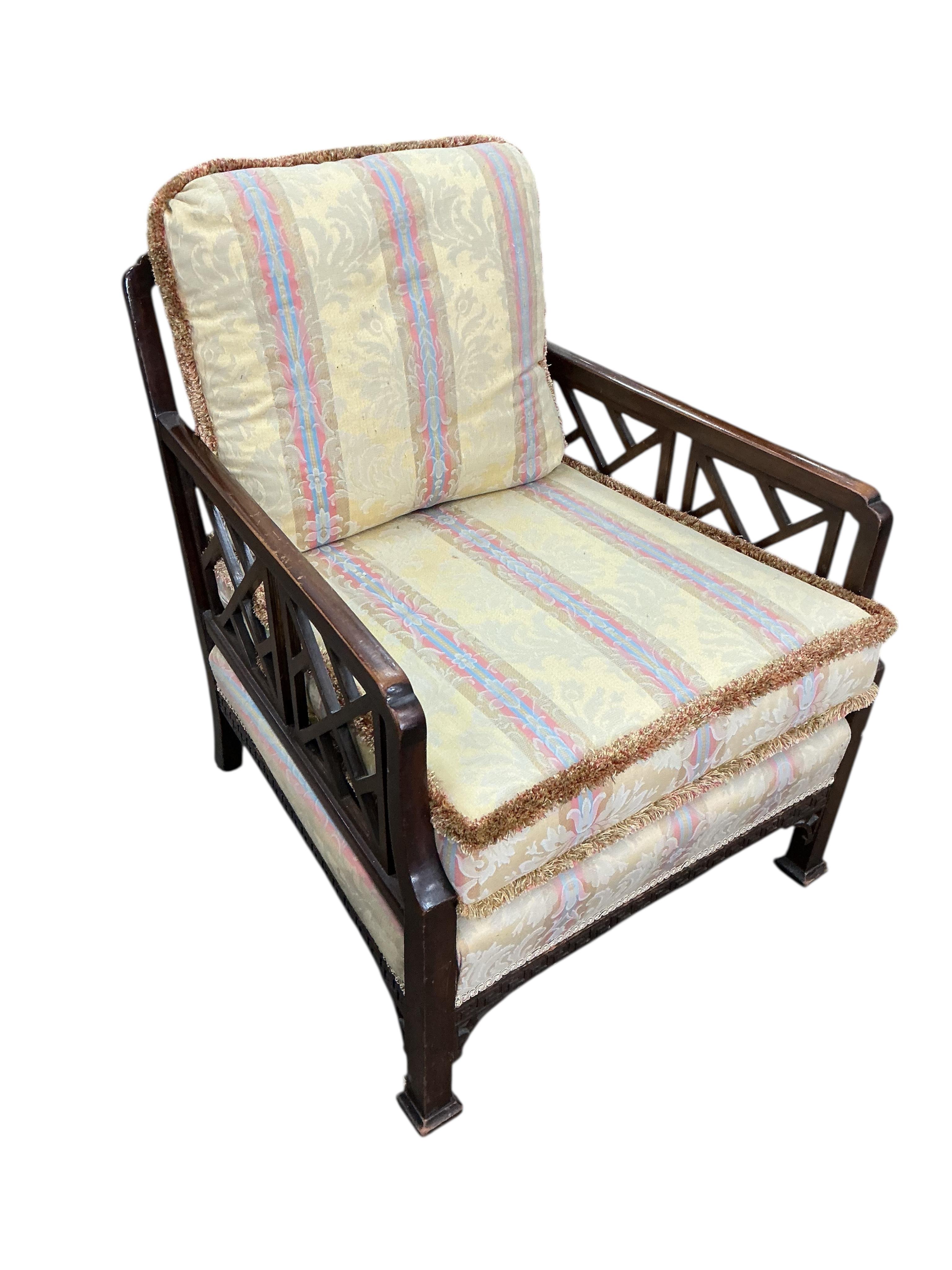 An early 20th century mahogany three piece suite comprising a sofa, width 134cm, depth 70cm, height 76cm and matching armchairs with fretwork sides